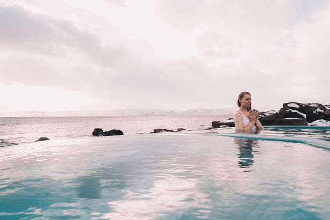 Woman sitting in pool near stones