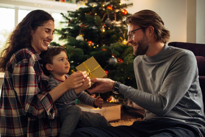 Man giving Christmas gift to his son and wife