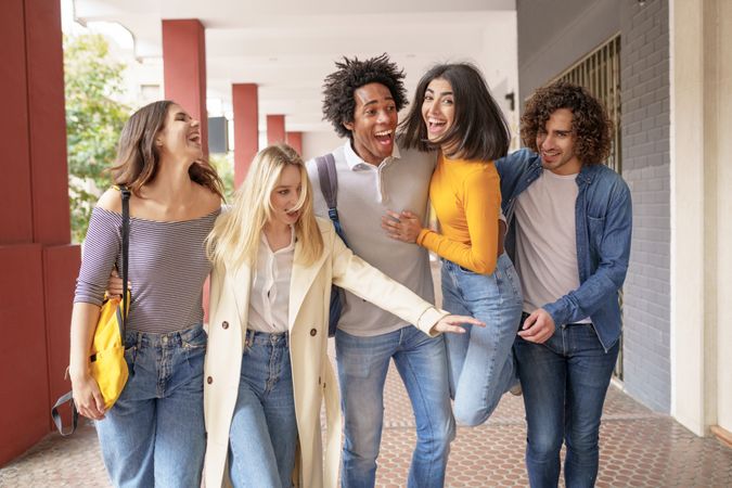 Multi-ethnic group of friends strolling down the street outside and goofing around