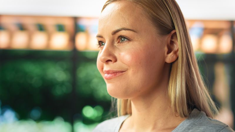 Authentic Portrait of Young Female in Kitchen Room at Home Looking Thoughtfully at Her Backyard.