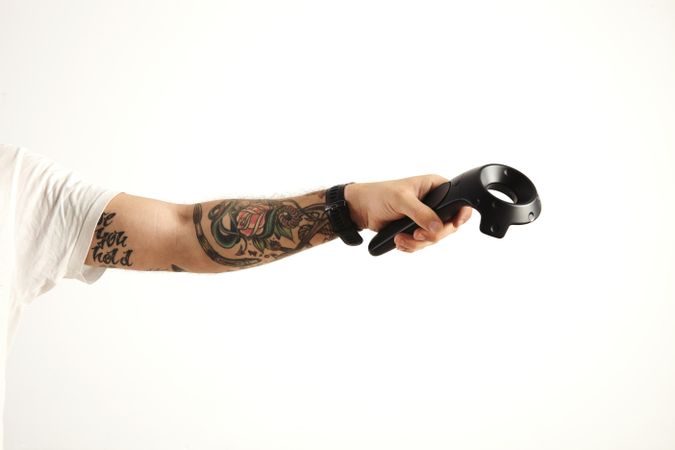 Tattooed hand holds VR remote controller