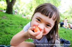 Young girl eating apricot in the park 41agg4