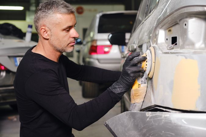 Mechanic grinding paint from car detail