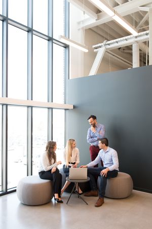 Stylish coworkers gathering around laptop in office