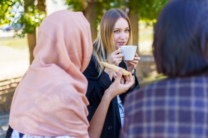 Three women snacking and drinking coffee outside