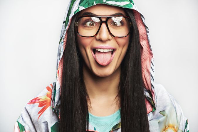 Woman pictured in colorful printed floral hoodie and glasses making a funny face for the camera