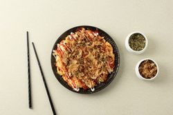 Top view of plate of okonomiyaki served with chilli sauce and mayonnaise