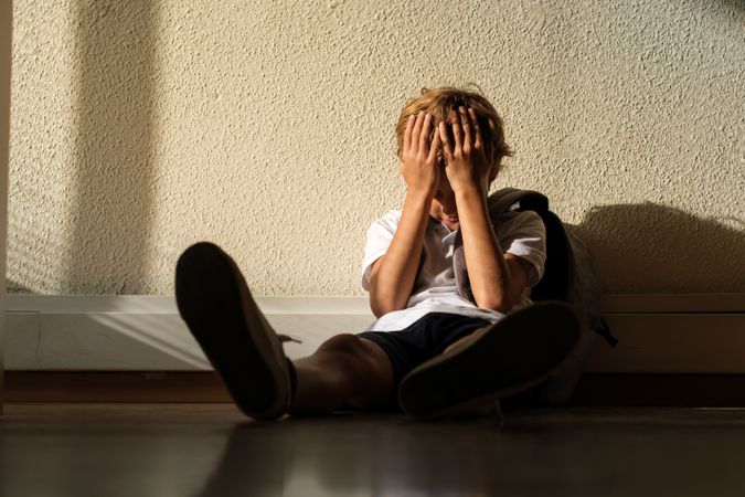 Lonely pupil covering face in classroom