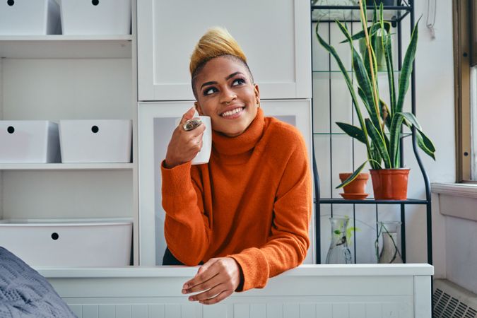 Smiling Black woman with a cup of coffee in a bright modern home