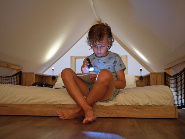 Serious boy reading with flashlight