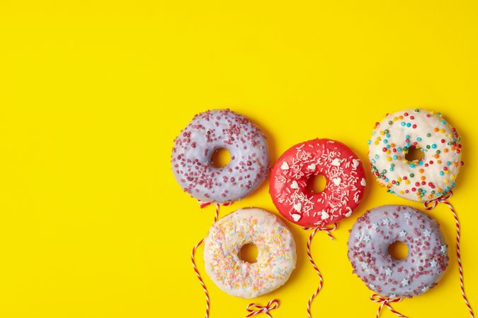 Concept of balloons made of donuts on yellow background
