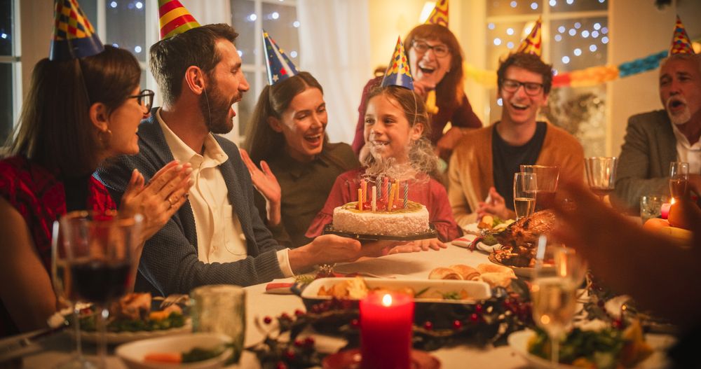 Father is Holding a Celebratory Cake, Little Daughter is Blowing Out Candles and Making a Joyful Wish.