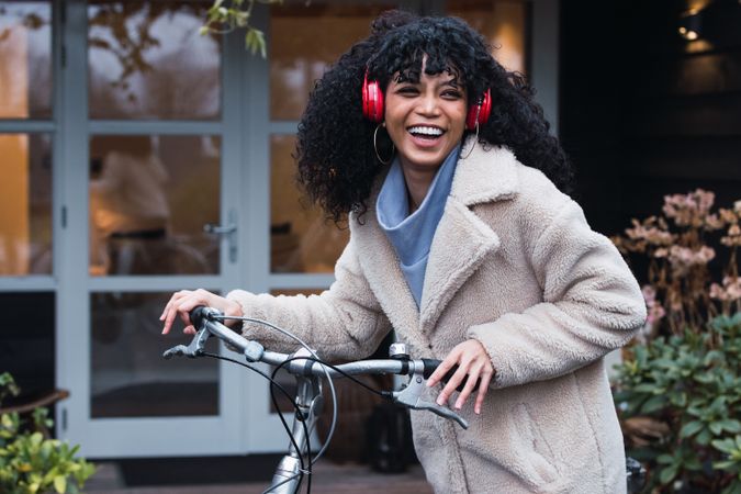 Cheerful Black woman in headphones with bicycle