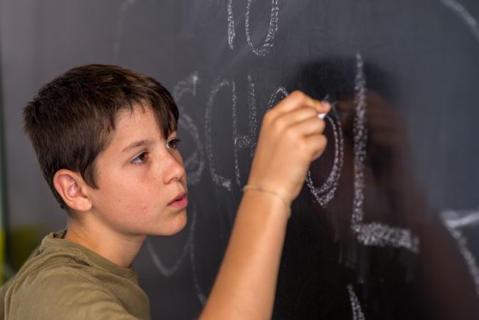 Teenage male writing on chalkboard