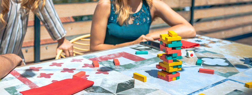 tower of game blocks over table with unrecognizable people playing in a rooftop party