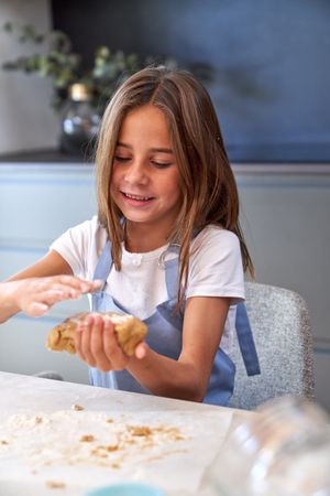 Content girl kneading dough in kitchen