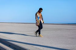 Black man walking and looking down while wearing eyeglasses and loud outside