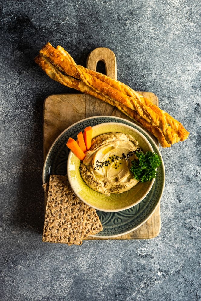 Top view of hummus dish in bowl on grey counter with space for text