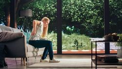 Young Adult Female Had to Sit Down on a Couch at Home Due to Discomfort in a Result of Leg Trauma or Arthritis. Joint and Knee Injury Concept.