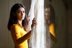 Woman opening curtains and gazing out the window
