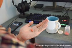 Person sitting at desk with medication in palm of hand 5r9qgd