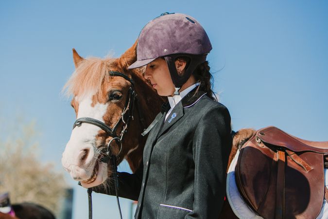 Woman in jockey outfit standing with horse