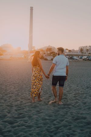Lovely couple walking holding hands on sandy beach