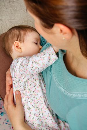 Cute baby girl breastfeeding with mother, vertical