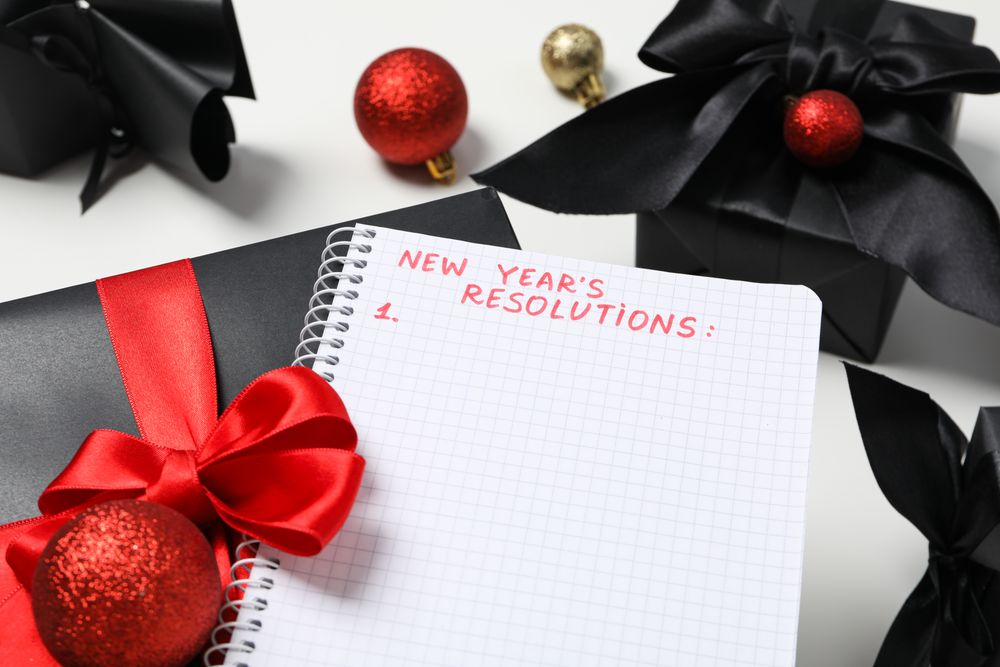 Gift boxes, decorations and notepad with text on light background, close up