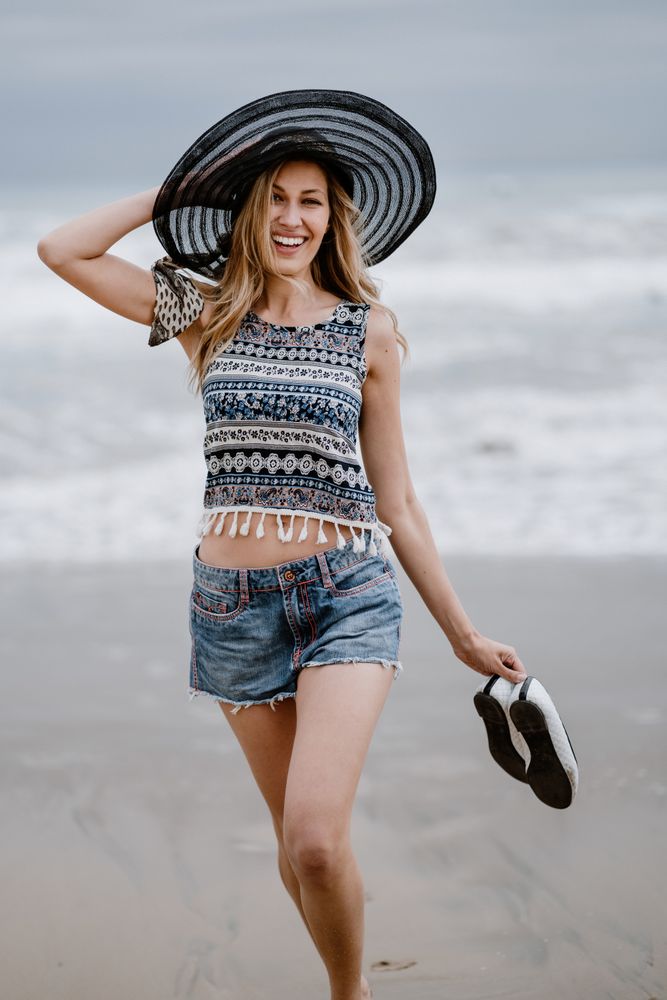 Young female walking barefoot on sandy beach