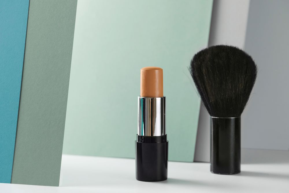 Concealer stick and make up brush on modern background