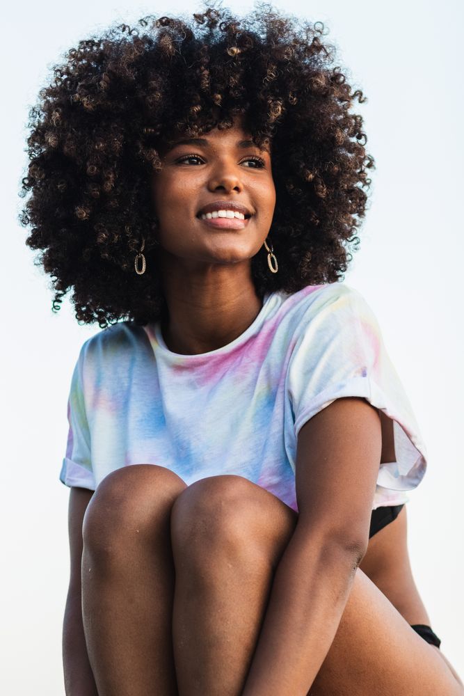 Delighted Black woman laughing at seaside