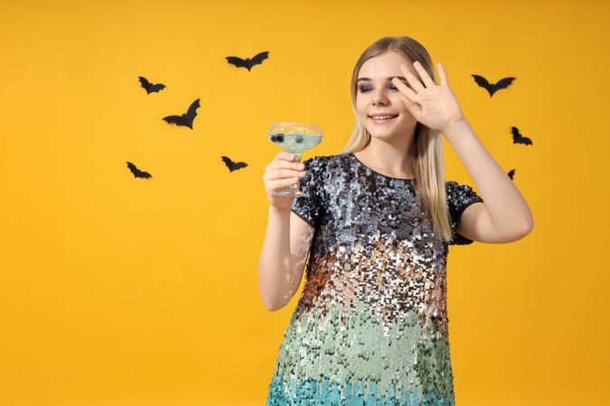 A woman at a party in the style of Halloween with a cocktail in her hands