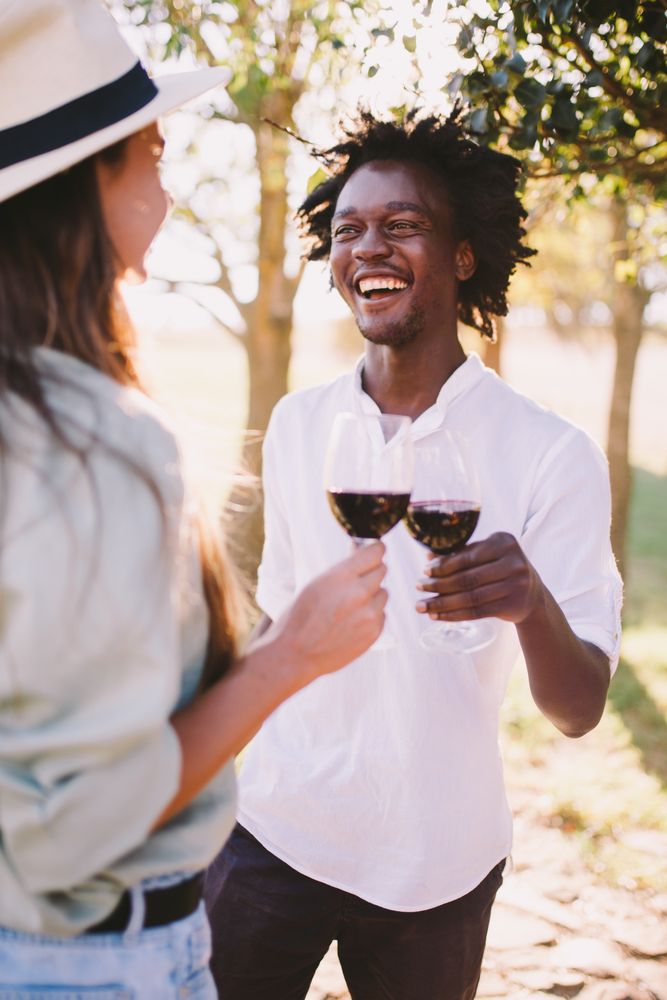A man and woman talking outside holding wine