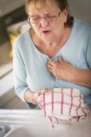 Older Adult Woman At Sink With Chest Pains