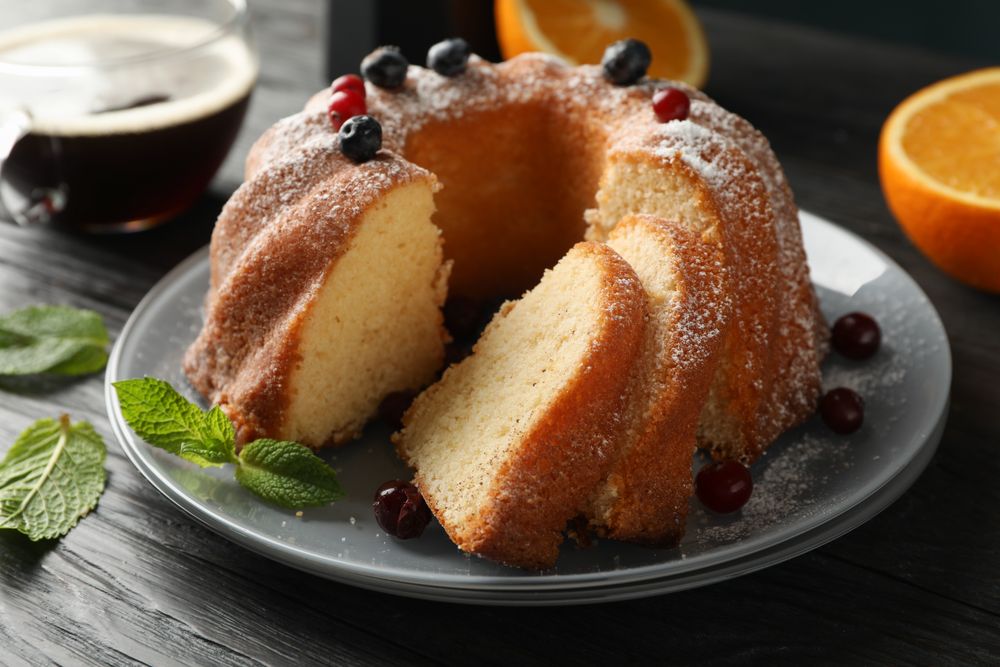 Cake with powdered sugar, berries and mint on wooden background, close up