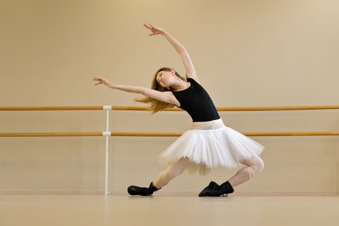 Ballerina in shoes and tutu, reaching out with arms