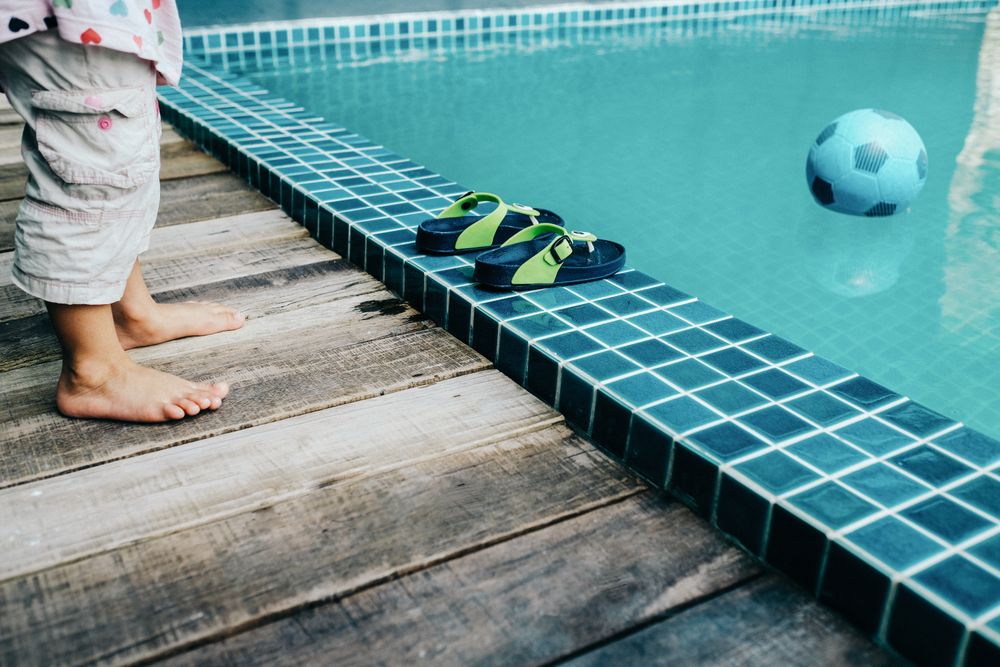 Feet of child on the side of the pool looking in