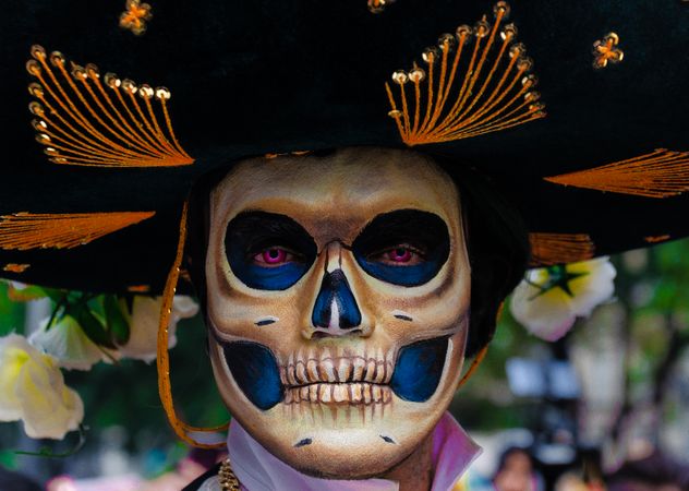 Portrait of man with sugar skull face paint and sombrero hat