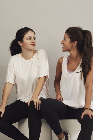 Happy young sportswomen resting after training in studio