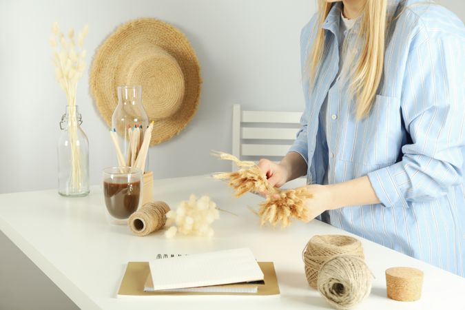 Female in blue striped shirt crafting a dried floral arrangement