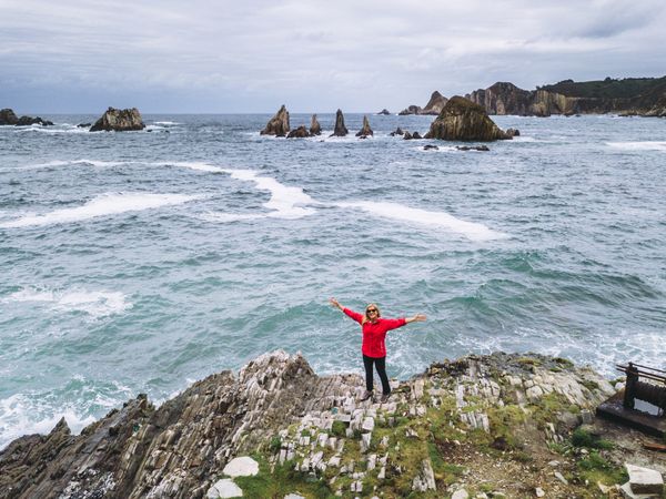 Woman standing on stony green seashore