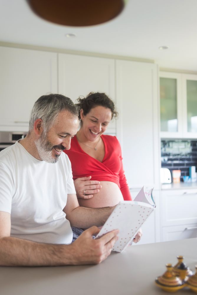 Laughing couple looking through book in kitchen