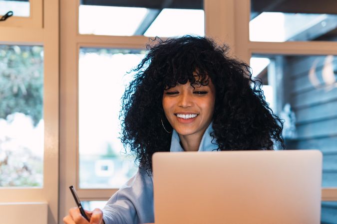 Black woman working on laptop and writing notes