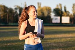 An athletic woman resting with her smartphone after running.