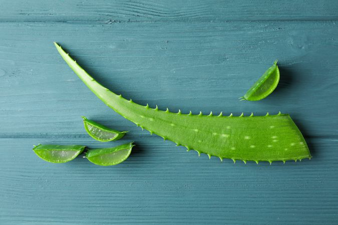 Aloe vera leaf and slices on wooden table, space for text. Natural treatment