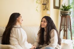 Smiling Young woman talking with her mother sitting on a sofa at home.
