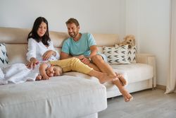 Pregnant mother and father looking at sleeping daughter in living room