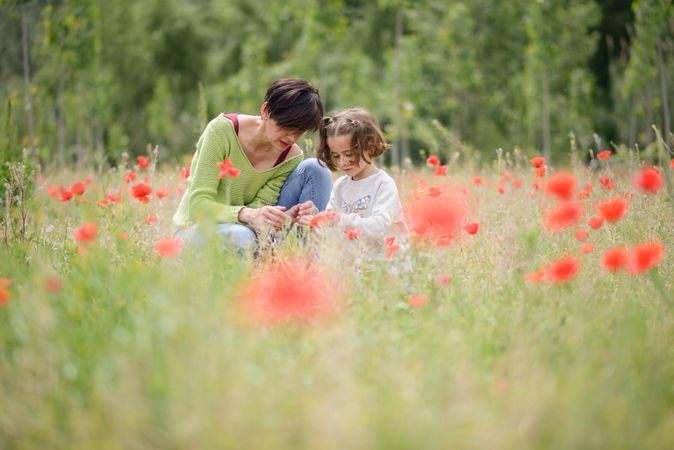 Woman and girl crouched down in poppy field