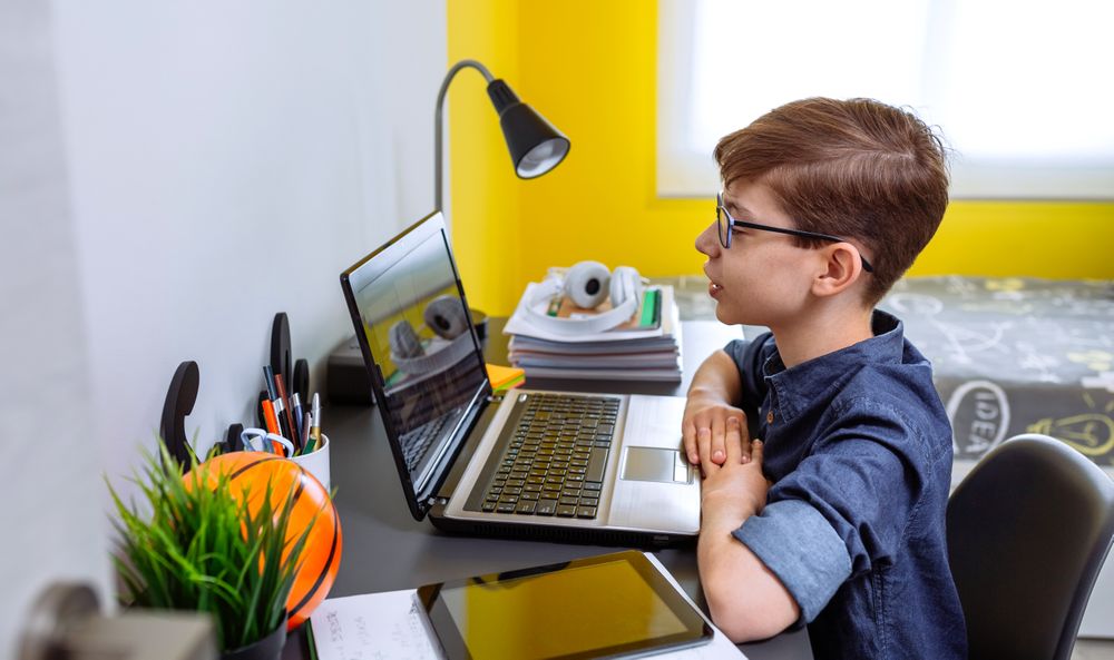Boy receiving class at home with laptop from his bedroom